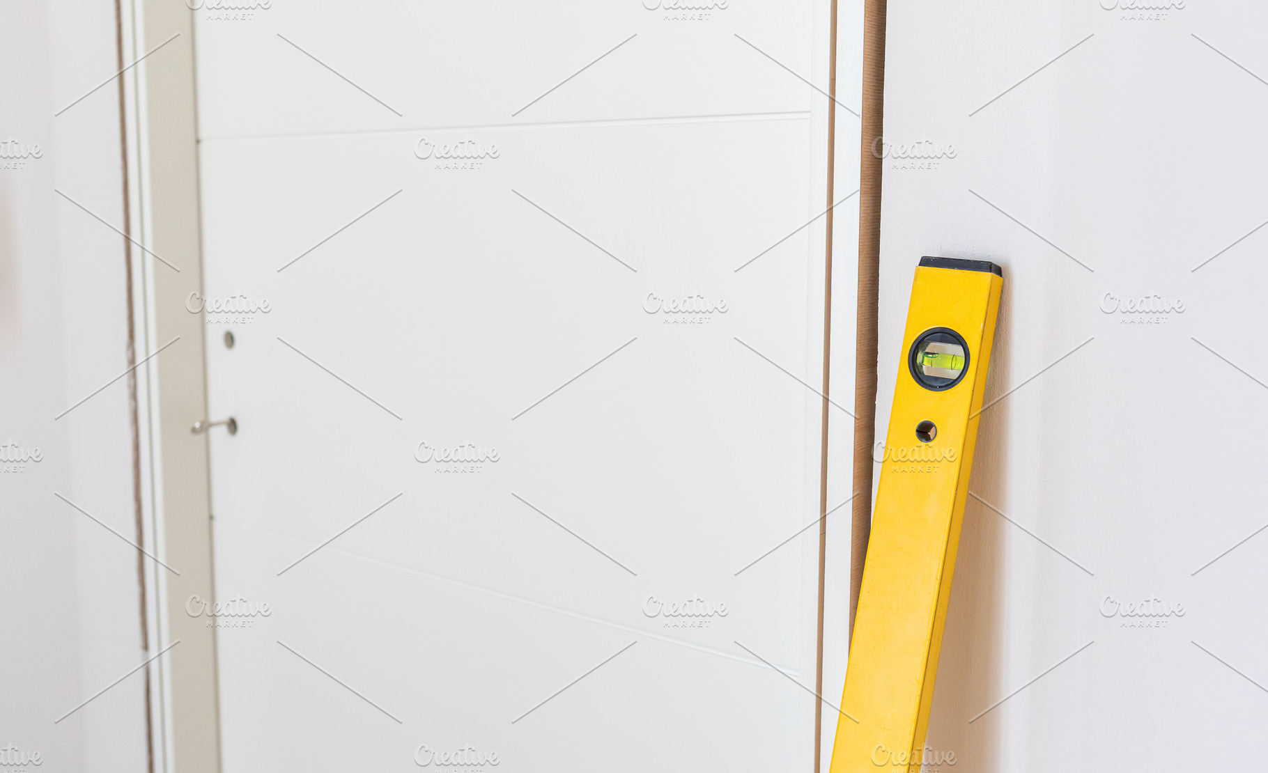Yellow spirit level leaning against white door during installation, an Architecture Photo by Antonio Gravante Market