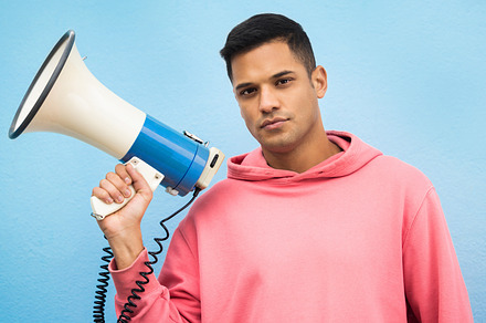 Man, portrait or megaphone for protest, human rights equality or freedom campaign on isolated blue background. Student, person or model with loud speaker for empowerment speech, justice or revolution, a Photo by Peopleimages.com