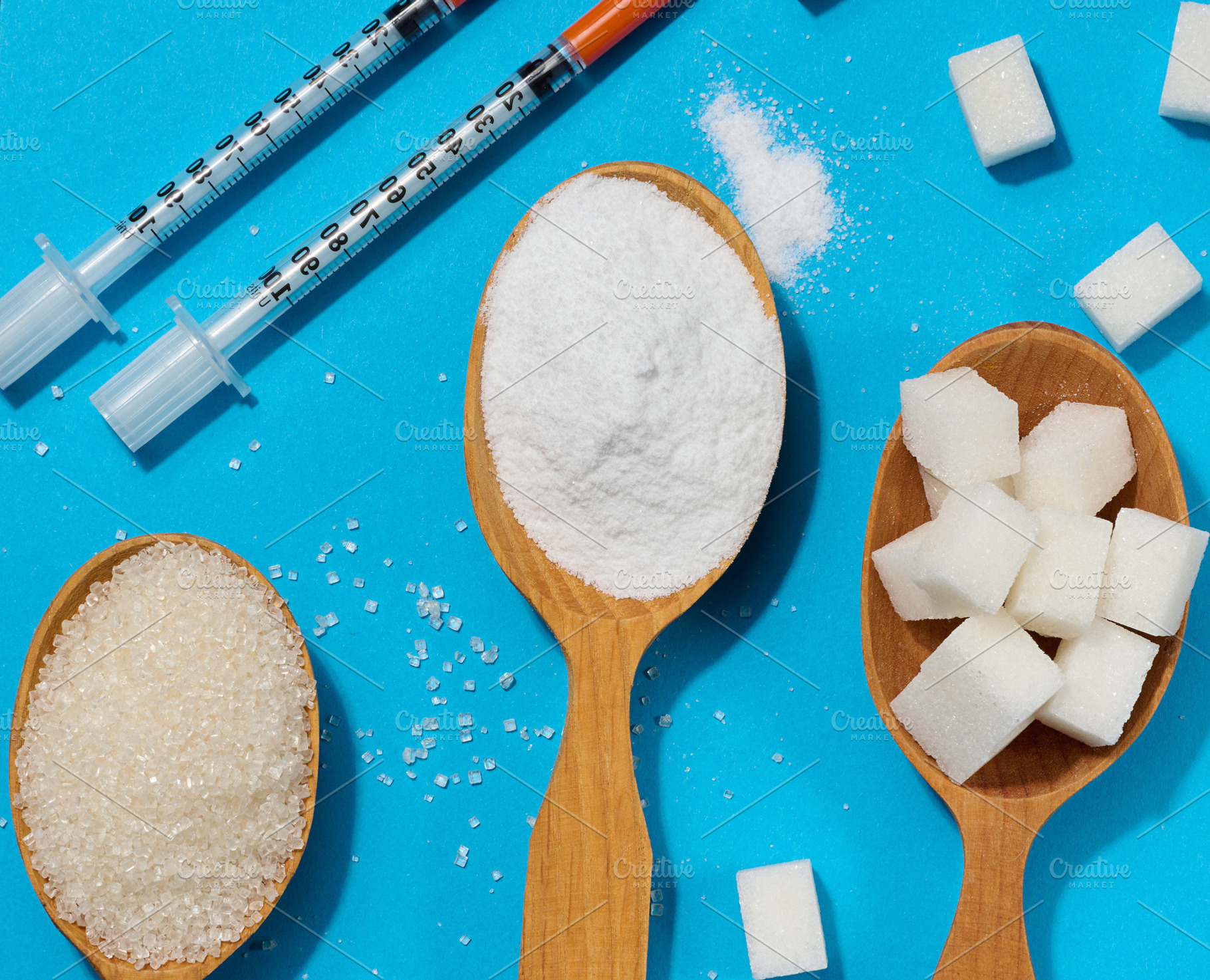 Sugar spoons and insulin syringes on a blue background symbolize, a Health & Medical Photo by ndanko