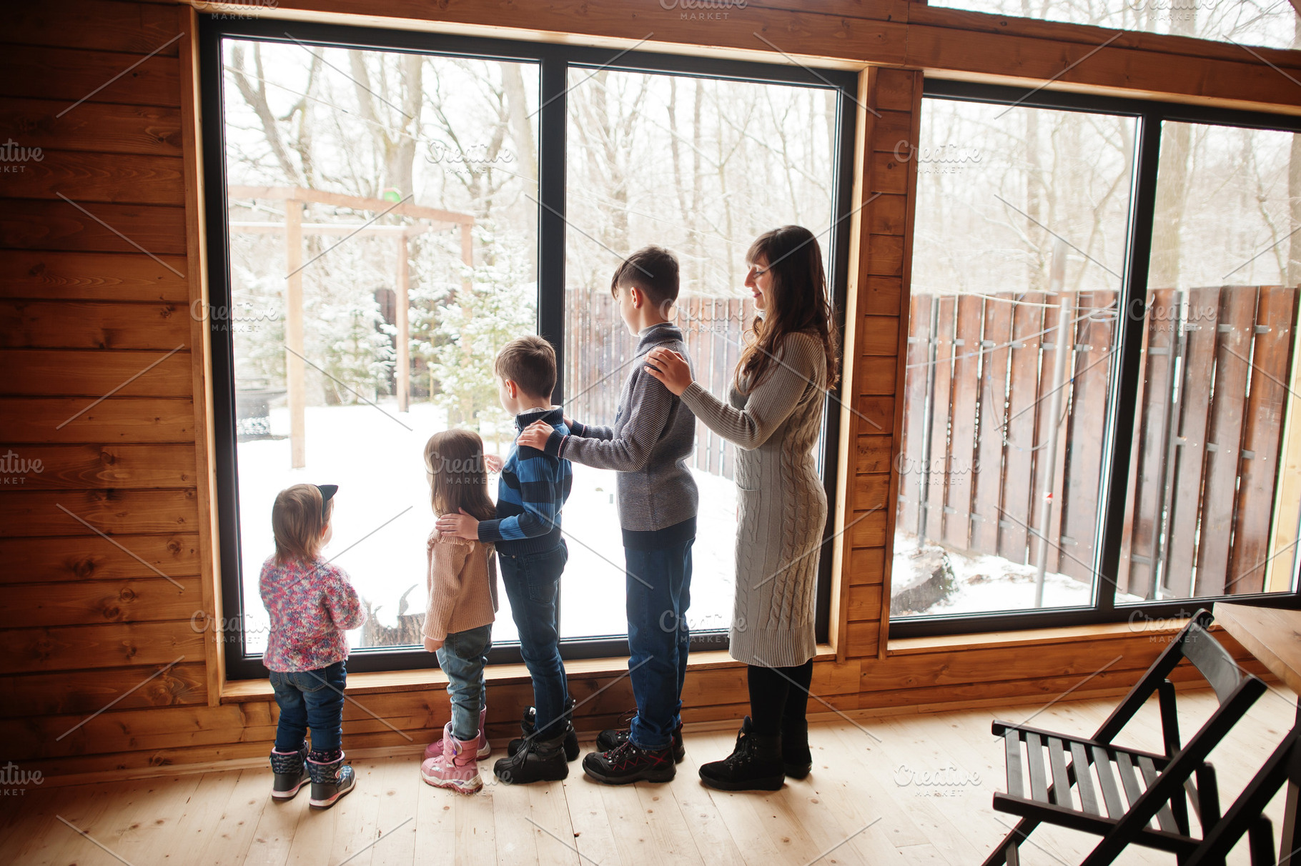 Mother and four kids in modern wooden house against large window, a Person Photo by AS photostudio
