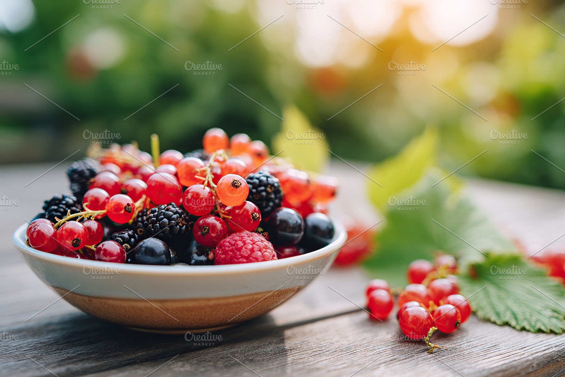 Freshly picked berries in a bowl on an outdoor table surrounded by nature, a Food & Drink Photo by AlyaAnd