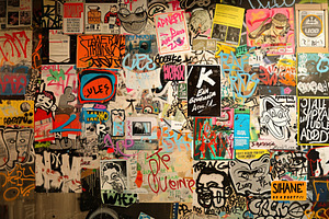 A Vibrant Wall Covered With An Eclectic Mix Of Graffiti, Posters, And Stickers.