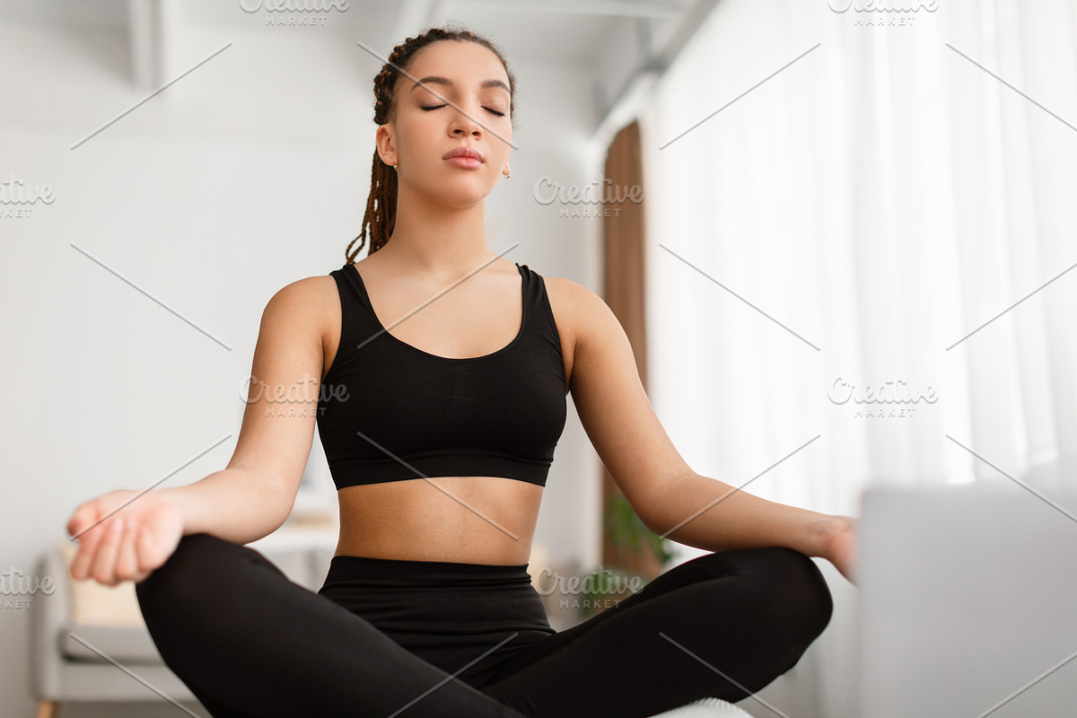 Calm African American Woman Meditating Sitting Doing Yoga At Home, a Photo by Prostock-Studio (Photo 2 of 2)