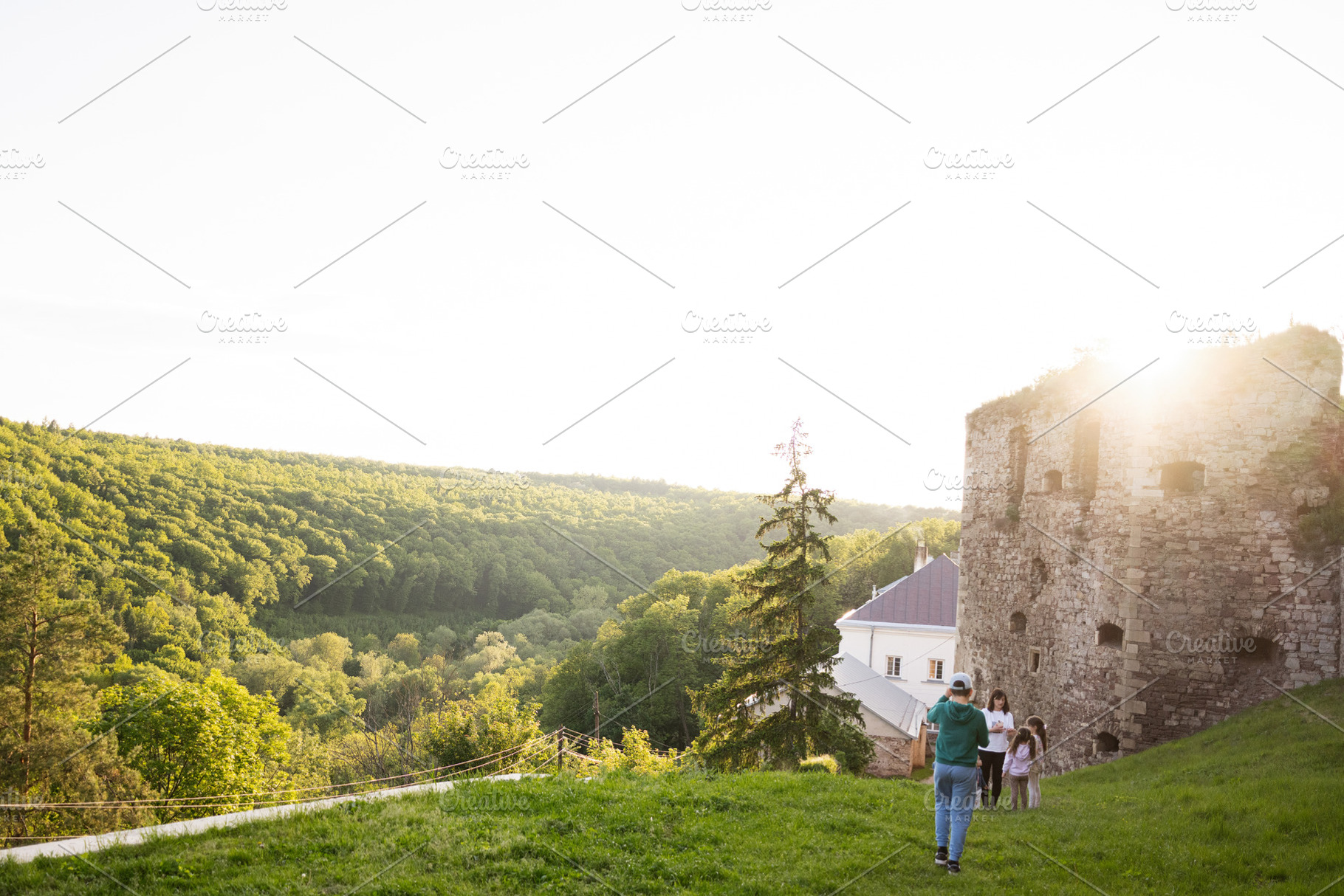 Family walking near ancient ruins in a lush green countryside during sunset, a Person Photo by AS photostudio