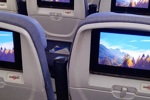 Interior of airplane cabin with personal screens on seats, a Transportation Photo by DanFLCreativo