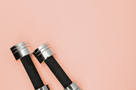 Metal small dumbbells on a pink containing workout, strength, and sport