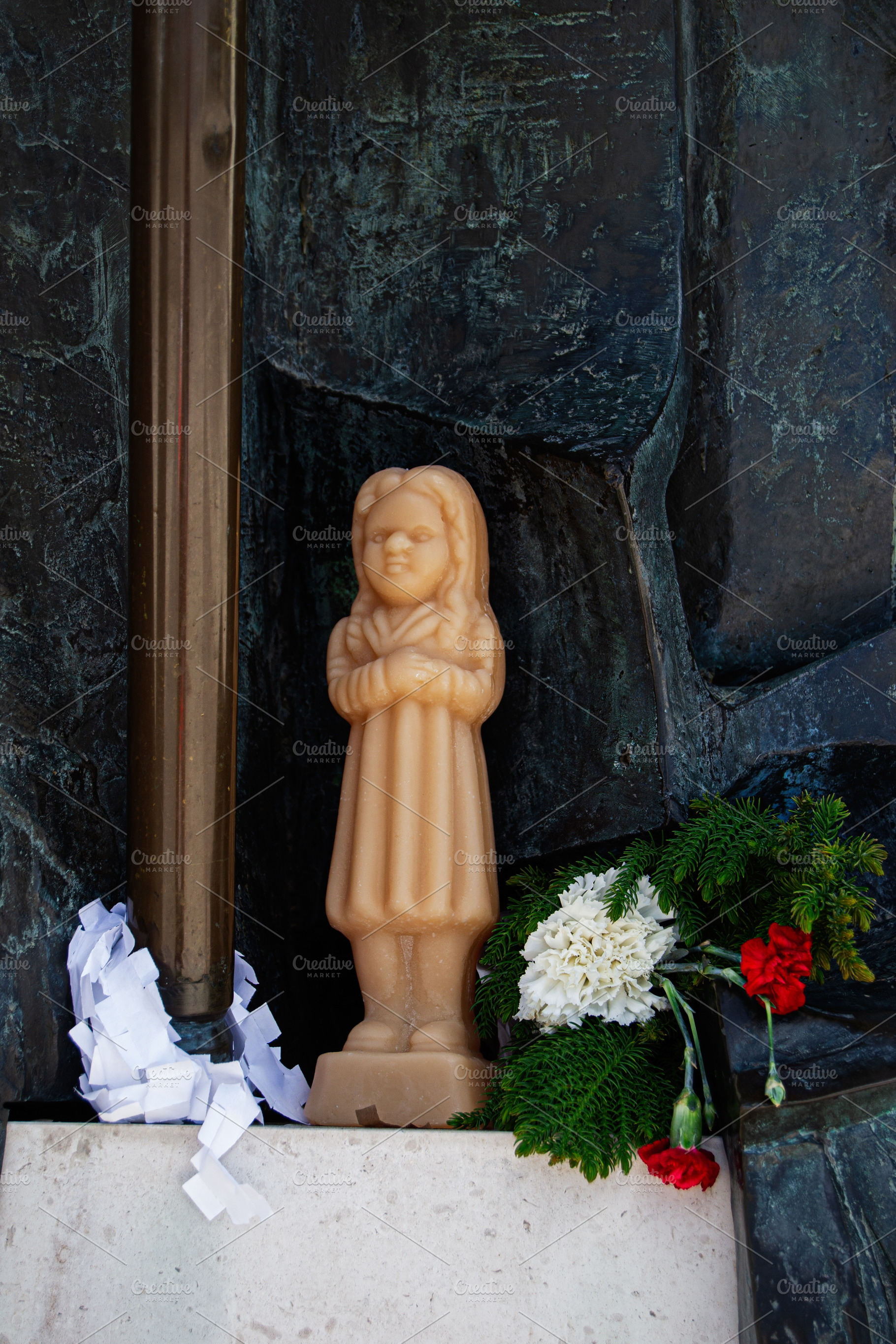 Wax devotional candle with flowers in sacred site in Fatima, Portugal, a Photo by AS photostudio