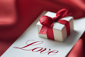 Little present with red ribbon on card with Love writing, symbol, a Photo by Studio ANNA