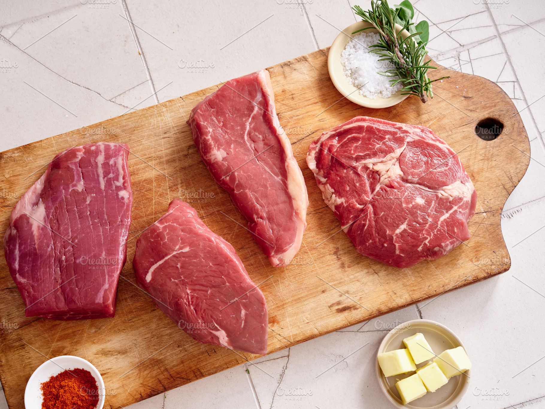 Raw meat cuts displayed on wooden board with seasoning and herbs at kitchen cou, a Food & Drink Photo by Asya Nurullina