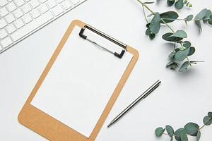 Clipboard with blank paper, pen, keyboard and eucalyptus branche, a Business Photo by Olena Rudo