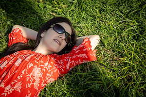 Woman in a red floral dress and sunglasses relaxing on a sunny p, a Person Photo by Imaginarium