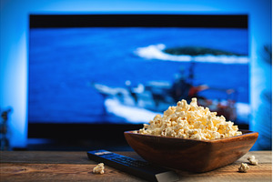 A wooden bowl of popcorn and remote, a Technology Photo by Budarinphoto