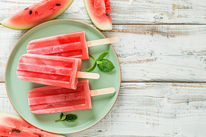 Ice cream popsicles with watermelon in plate on wooden background, a Food & Drink Photo by AlyaAnd