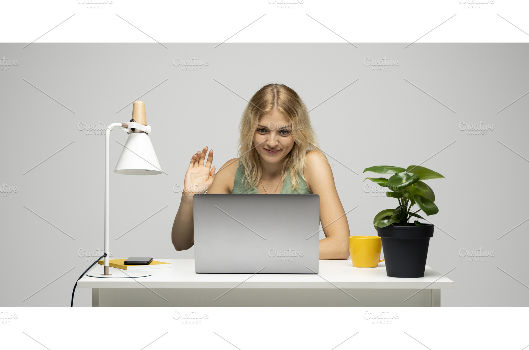 Smiling blonde woman waving hand, a Technology Photo by volodymyrshtun13795