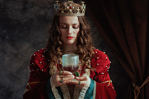 medieval queen in red dress with goblet and crown, a Person Photo by Alliance Images
