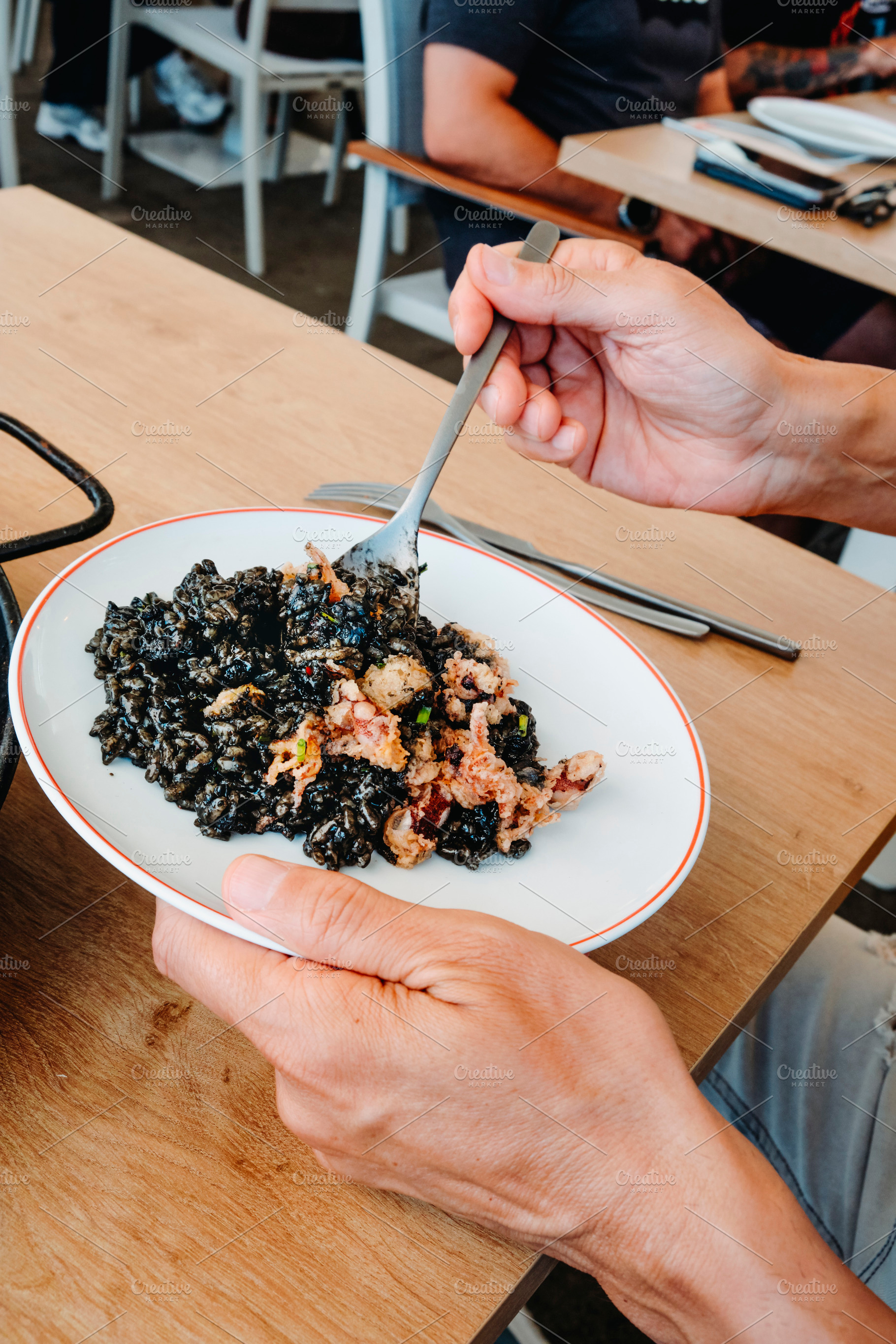 at a restaurant, a man serves himself arros negre, a Photo by Nito