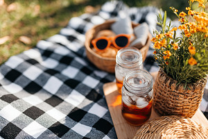 Picnic setup with refreshing drinks and flowers in a city park on a sunny day, a Photo by AlyaAnd