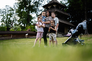 Mother standing with children near stroller in lush green outdoors setting, a Person Photo by AS photostudio