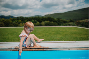 Child sitting by the poolside and, a Person Photo by HalfPoint