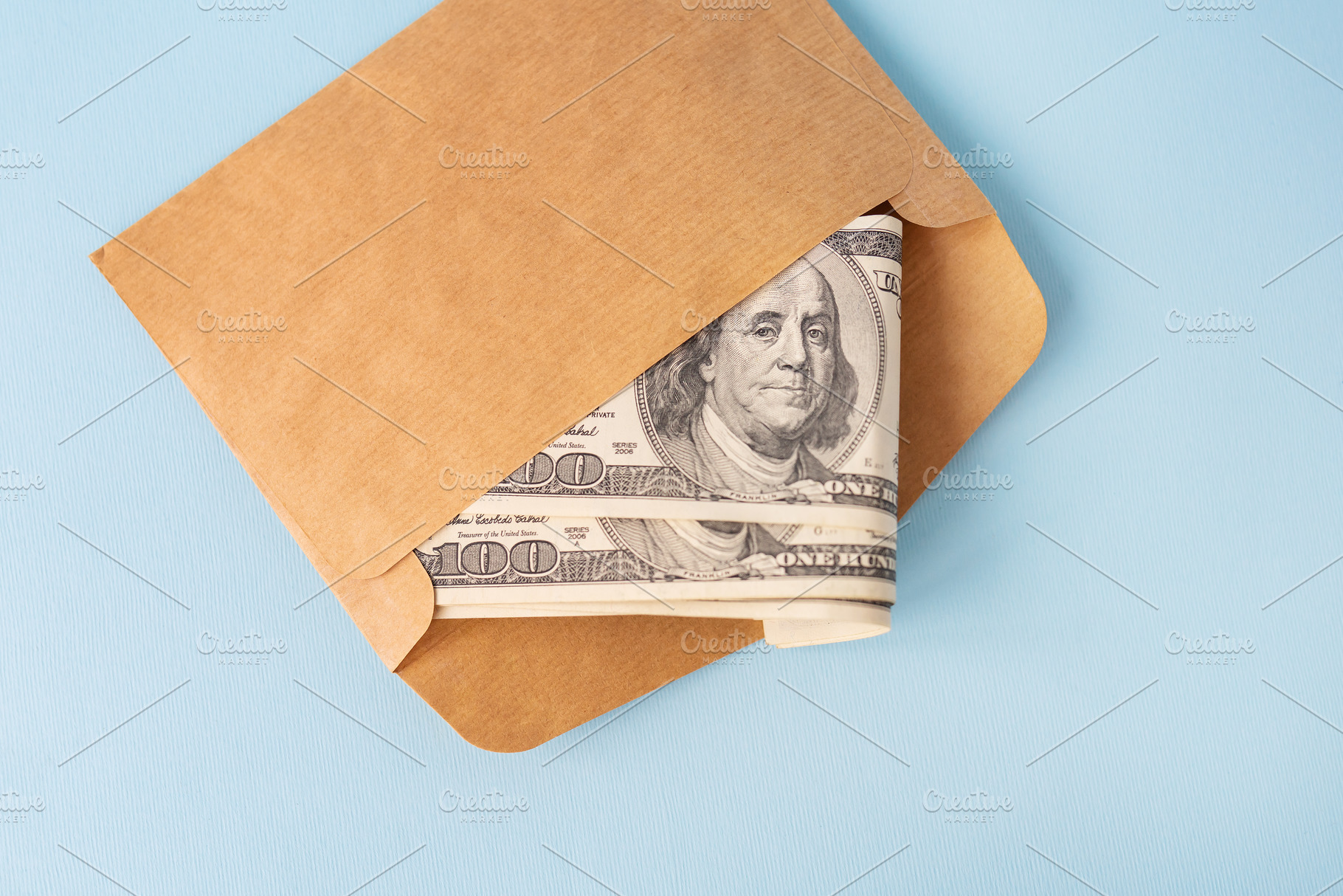 Stash of money in dollar bills coming out of an envelope on a blue background., a Business Photo by Artsaba Family