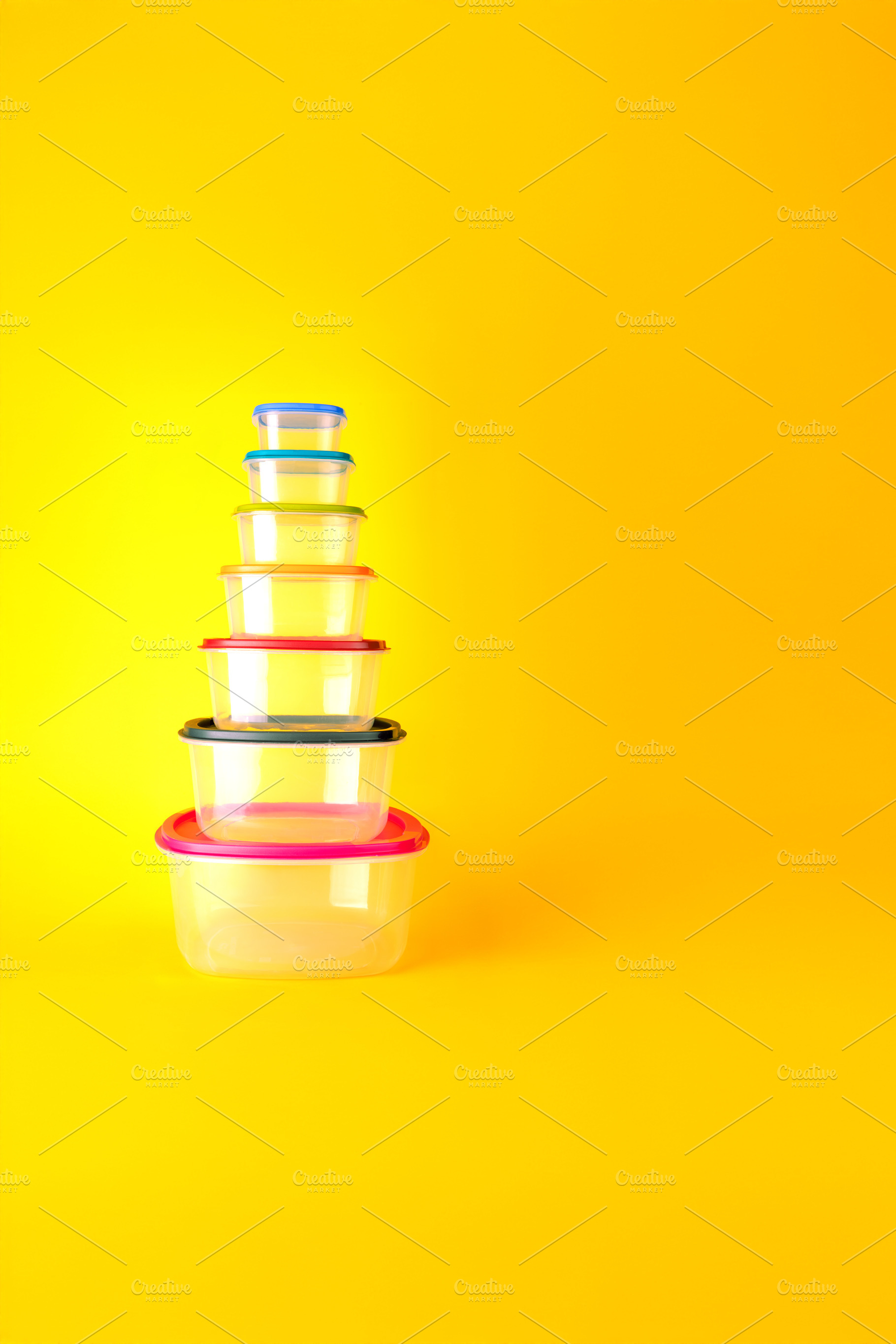 Stack of transparent plastic food containers with colorful lids,, a Background Photo by Ales Munt