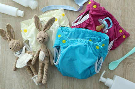 Concept of baby clothes with reusable diapers on wooden backgrou