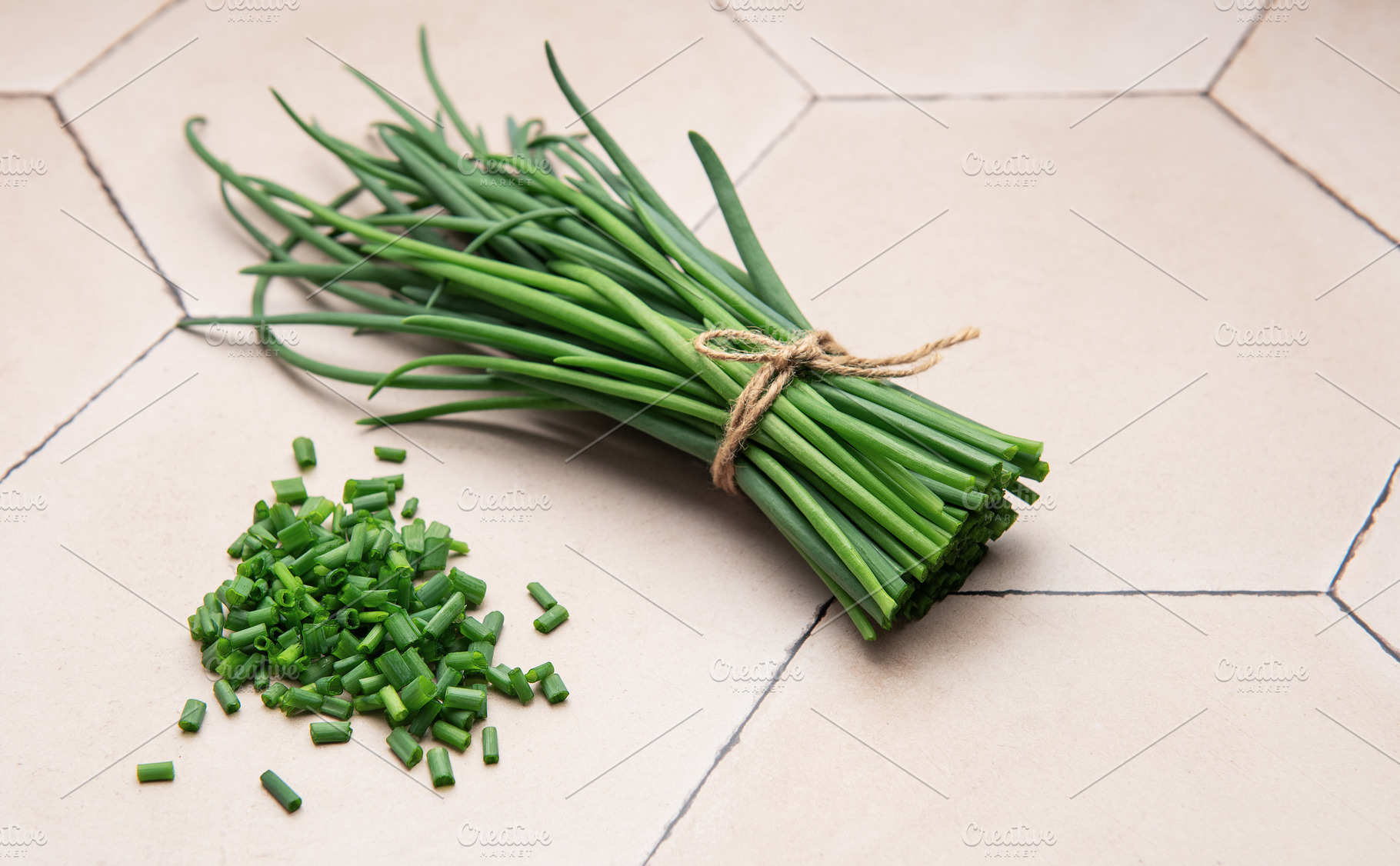 Freshly cut chives tied with twine on a tiled surface, a Photo by Olena Rudo