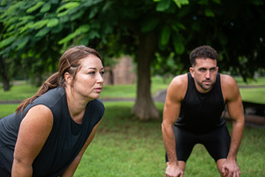 Tired man and woman resting after outdoor fitness workout in park