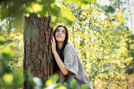 Young woman enjoying a peaceful moment by a tree in a lush green, a Person Photo by Olena Rudo