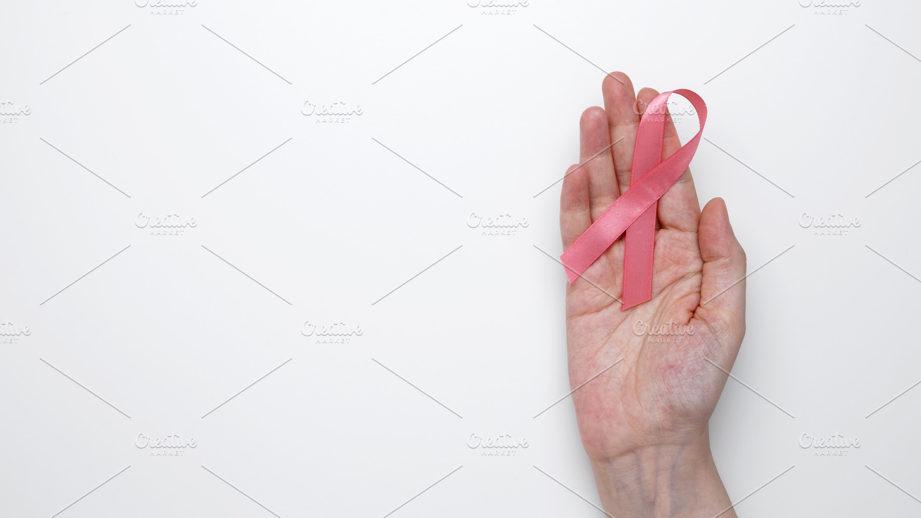 Symbol of breast cancer awareness. Woman hand holding pink ribbon, a Photo by matucha
