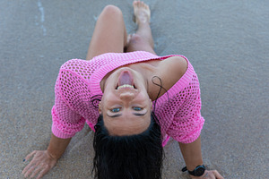 Smiling woman in pink sweater enjoying a sunny day on sandy beach, lying by the, a Holiday Photo by Ales Munt