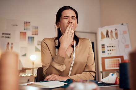 Tired fashion designer, woman and yawn while working at night in creative office, textile studio or startup. Exhausted, sleepy and overworked tailor yawning in burnout, stress and fatigue in workshop, a Photo by Peopleimages.com