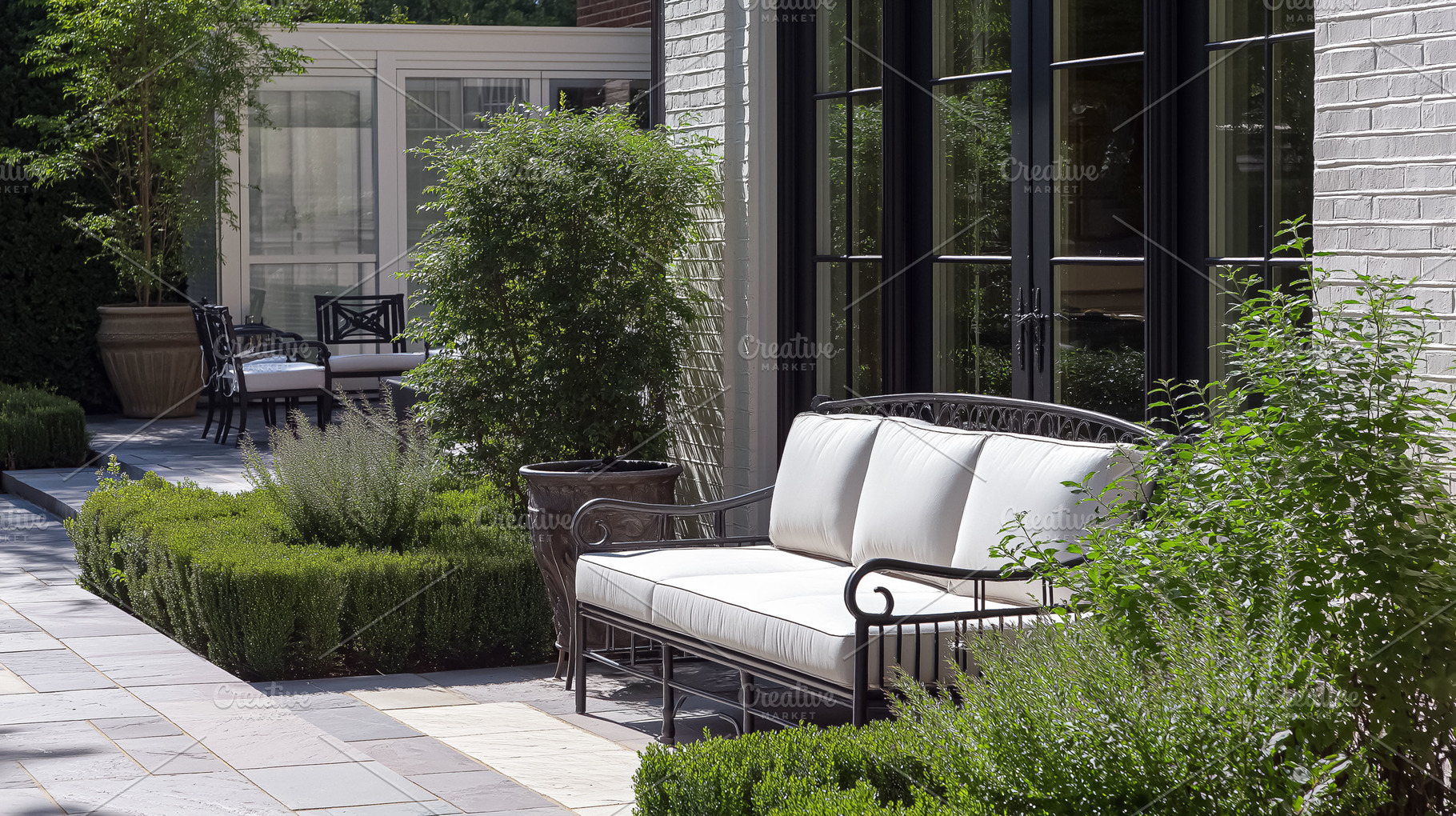 Outdoor elegantly furnished patio with comfortable white cushions on wrought ir, an Architecture Photo by Studio ANNA