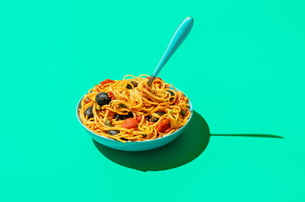 Spaghetti puttanesca bowl isolated on a green background, a Food & Drink Photo by YesPhotographers
