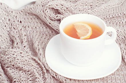 cup of tea on gray blanket in bed.