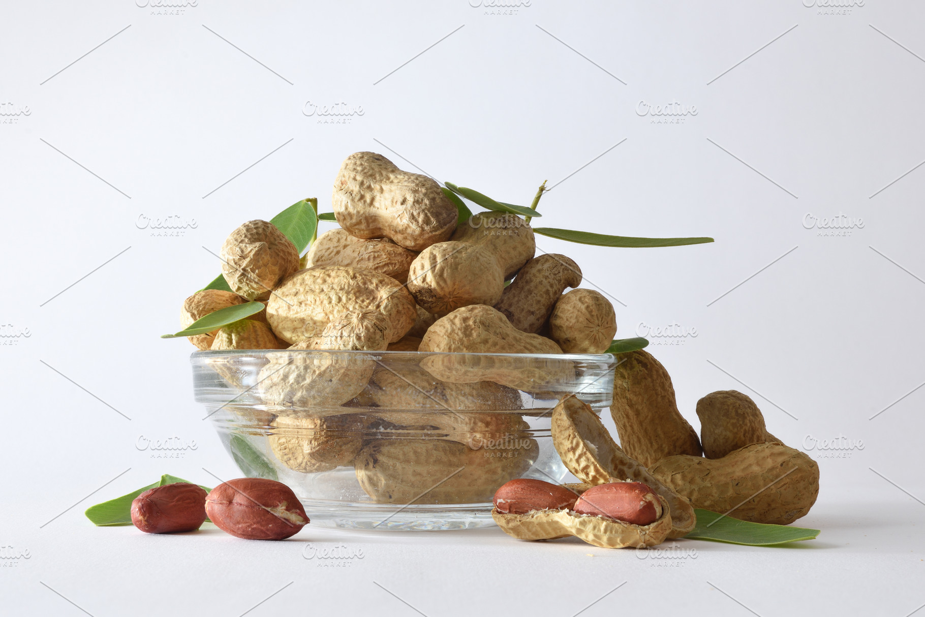 Glass bowl with shelled peanuts showing on white background, a Food & Drink Photo by Davizro's Market