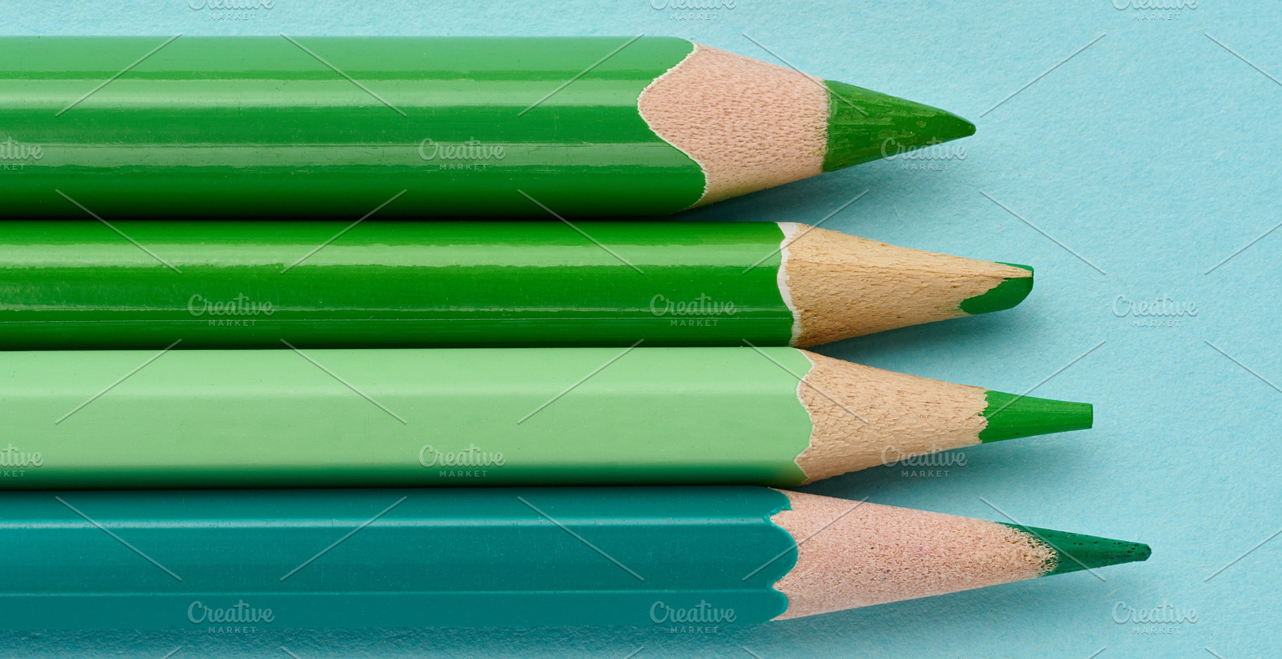 Row of green wooden pencils on a blue background, a School & Education Photo by ndanko