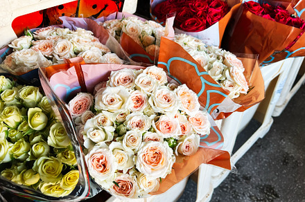 Bouquets of roses displayed for sale at a flower market on a sunny day, a Photo by AS photostudio