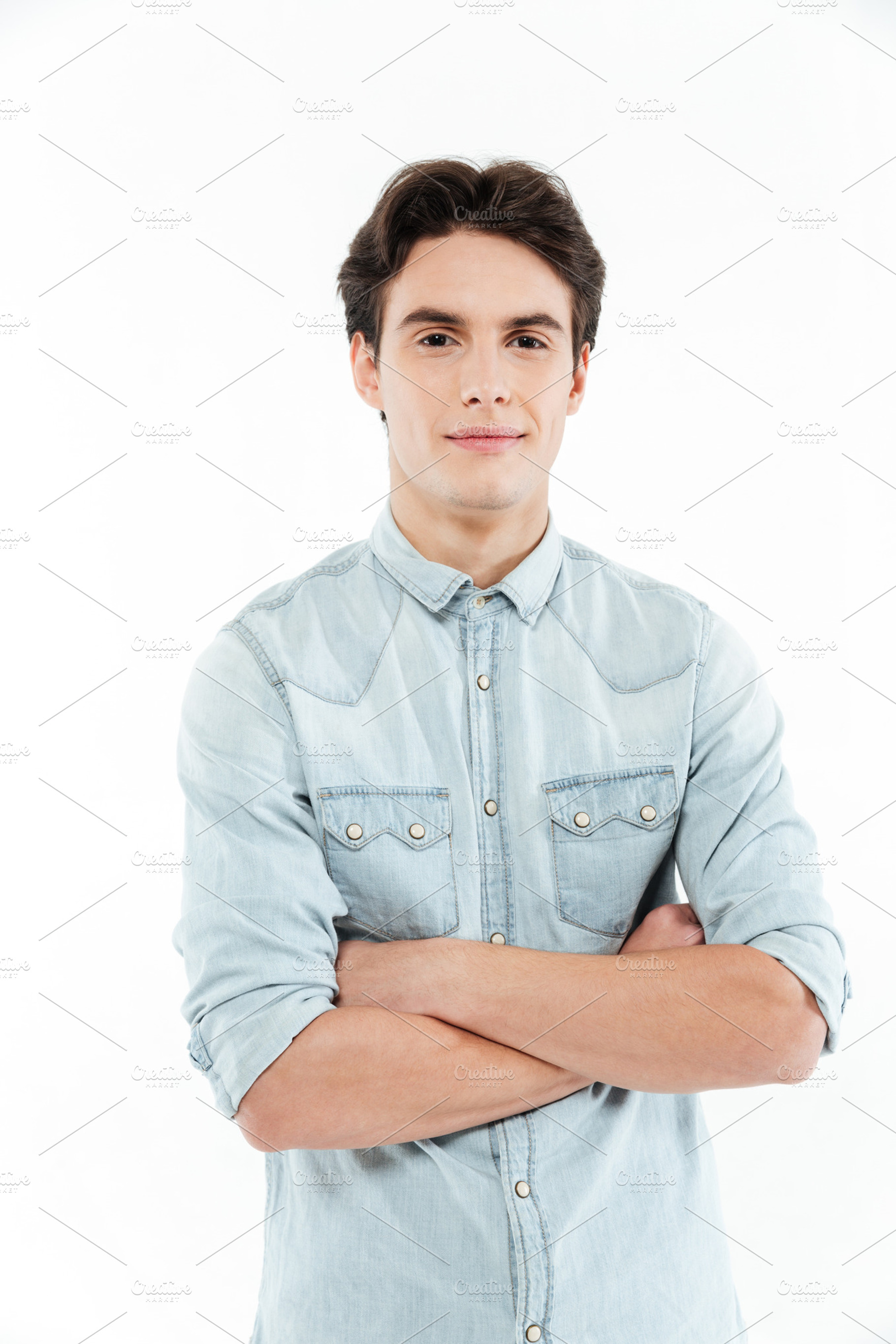 Young man standing with arms folded and looking at camera, a Person Photo by Dean Drobot