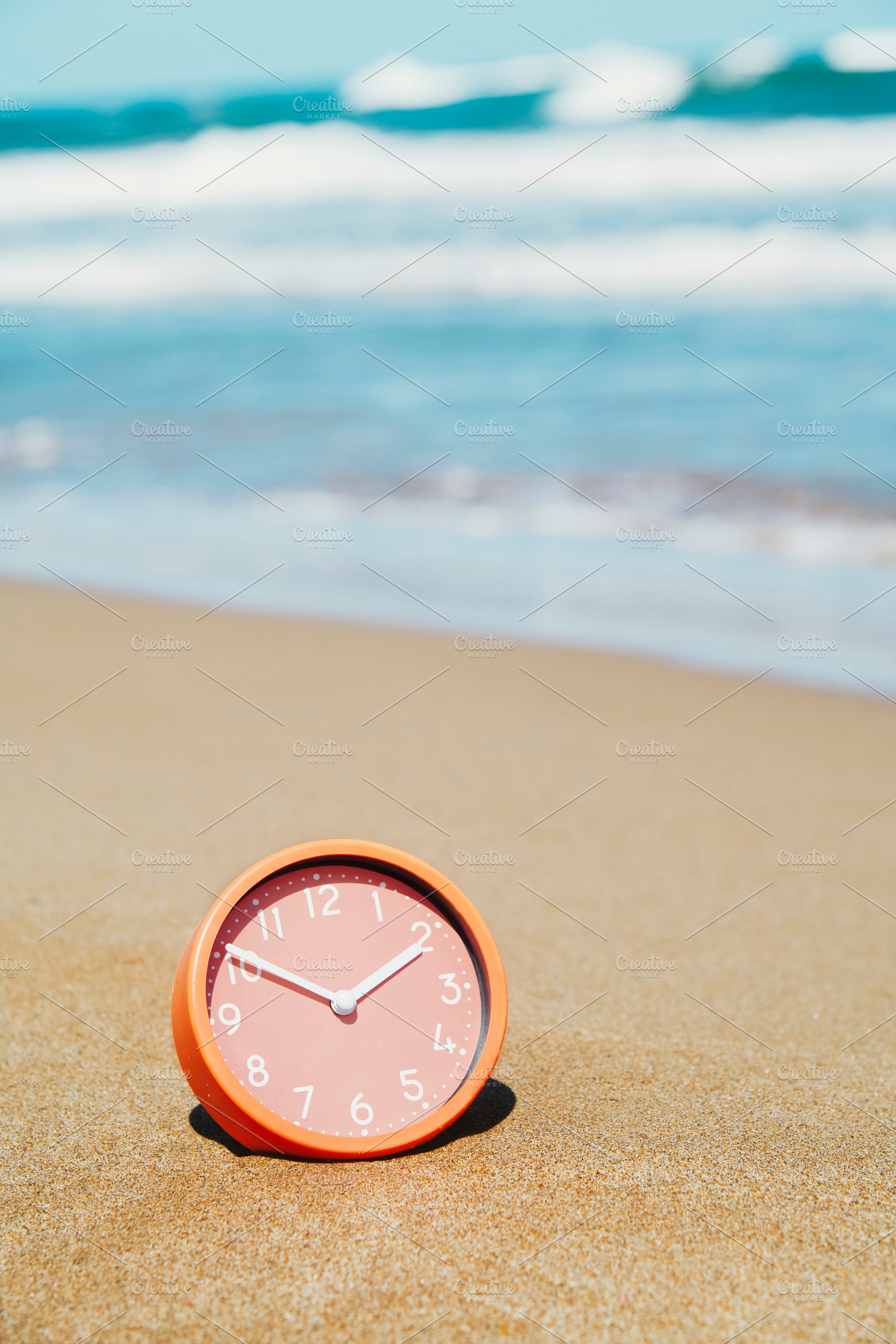 a clock rests in the sand at an empty beach, a Photo by Nito