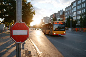 A red 'no entry' sign stands prominently as a city bus passes in the evening li, a Person Photo by ImageMir