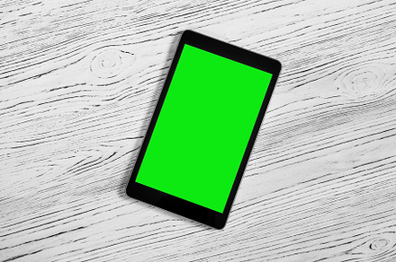 Black tablet with green screen on a wooden table mock up. Copy s, an Abstract Photo by Eugene_Photo