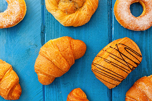 Delicious assorted pastries lying on blue wooden table for breakfast, a Food & Drink Photo by Antonio Gravante Market
