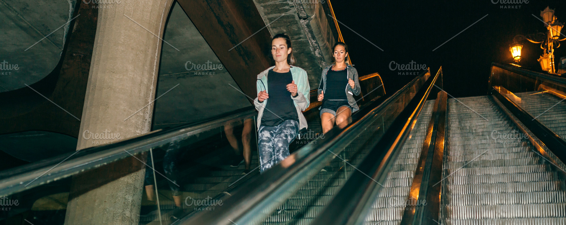 Women friends training running down escalator in city at night, a Sports & Recreation Photo by davidpereiras