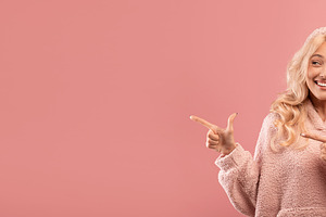 Excited young lady pointing and looking aside at empty space, demonstrating pla, a Photo by Prostock-Studio