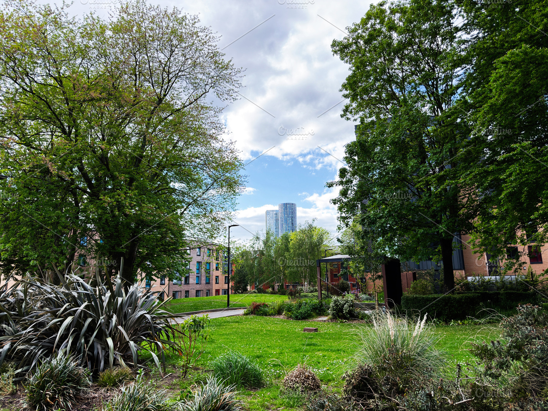 Urban park with trees and distant skyscraper in Manchester, UK r, a Photo by AS photostudio