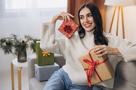Beautiful happy woman unwrapping New Year or Christmas presents
