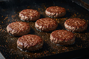 Juicy beef patties sizzling on a hot, a Food & Drink Photo by professorinc