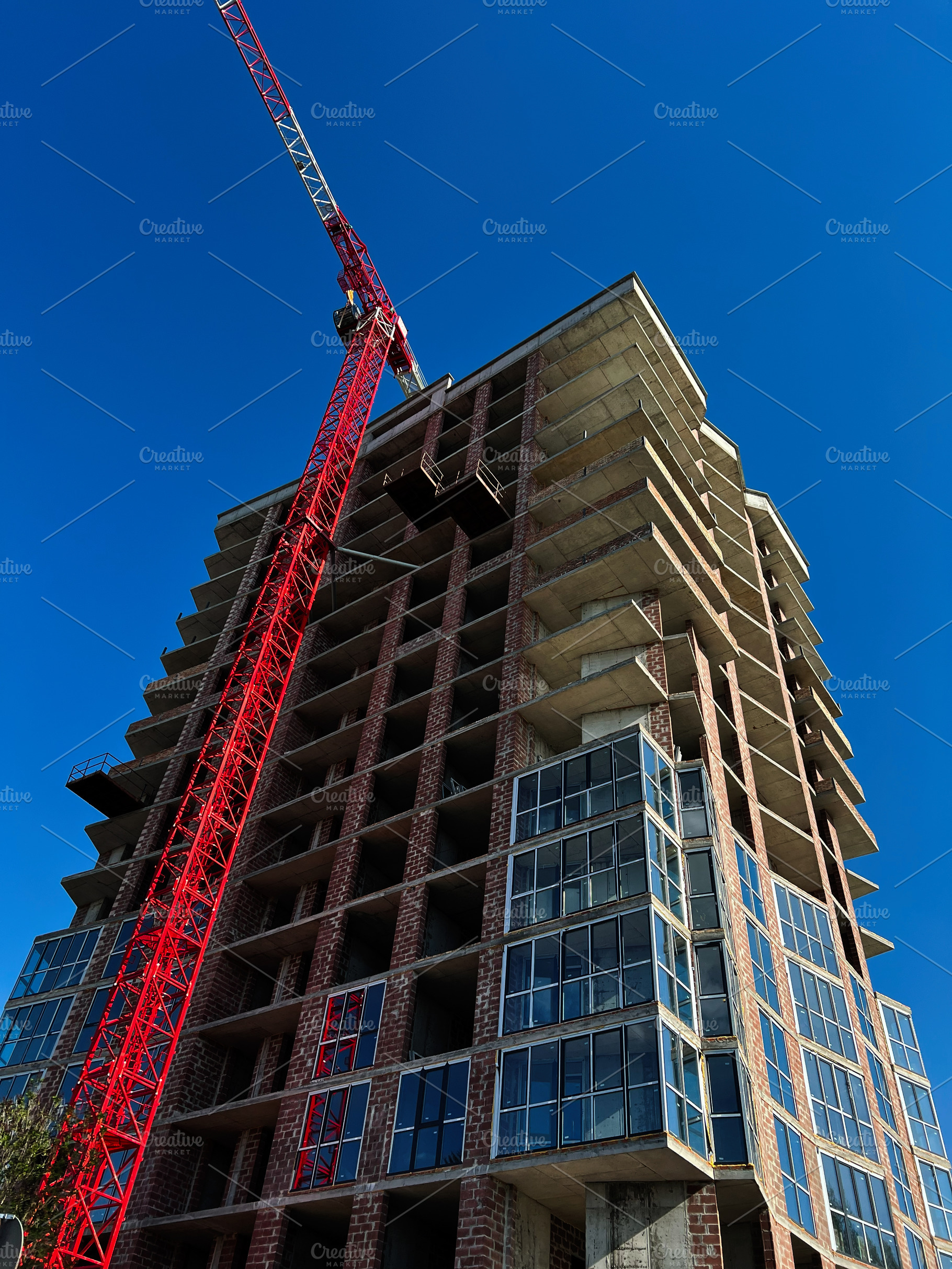 Modern urban building construction with crane under a clear blue sky, a Photo by AS photostudio