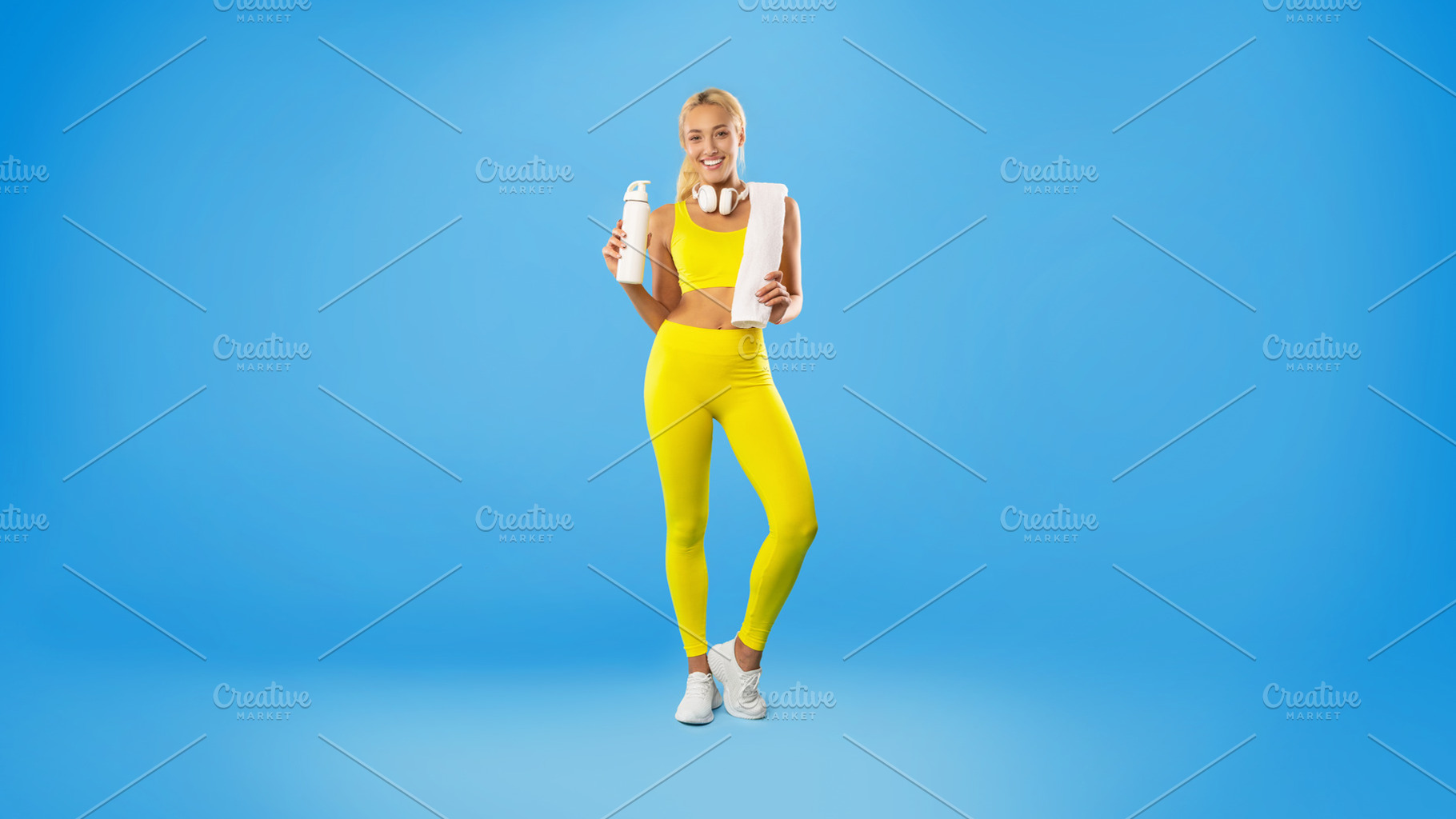 Sporty smiling woman posing at studio with water bottle, a Photo by Prostock-Studio